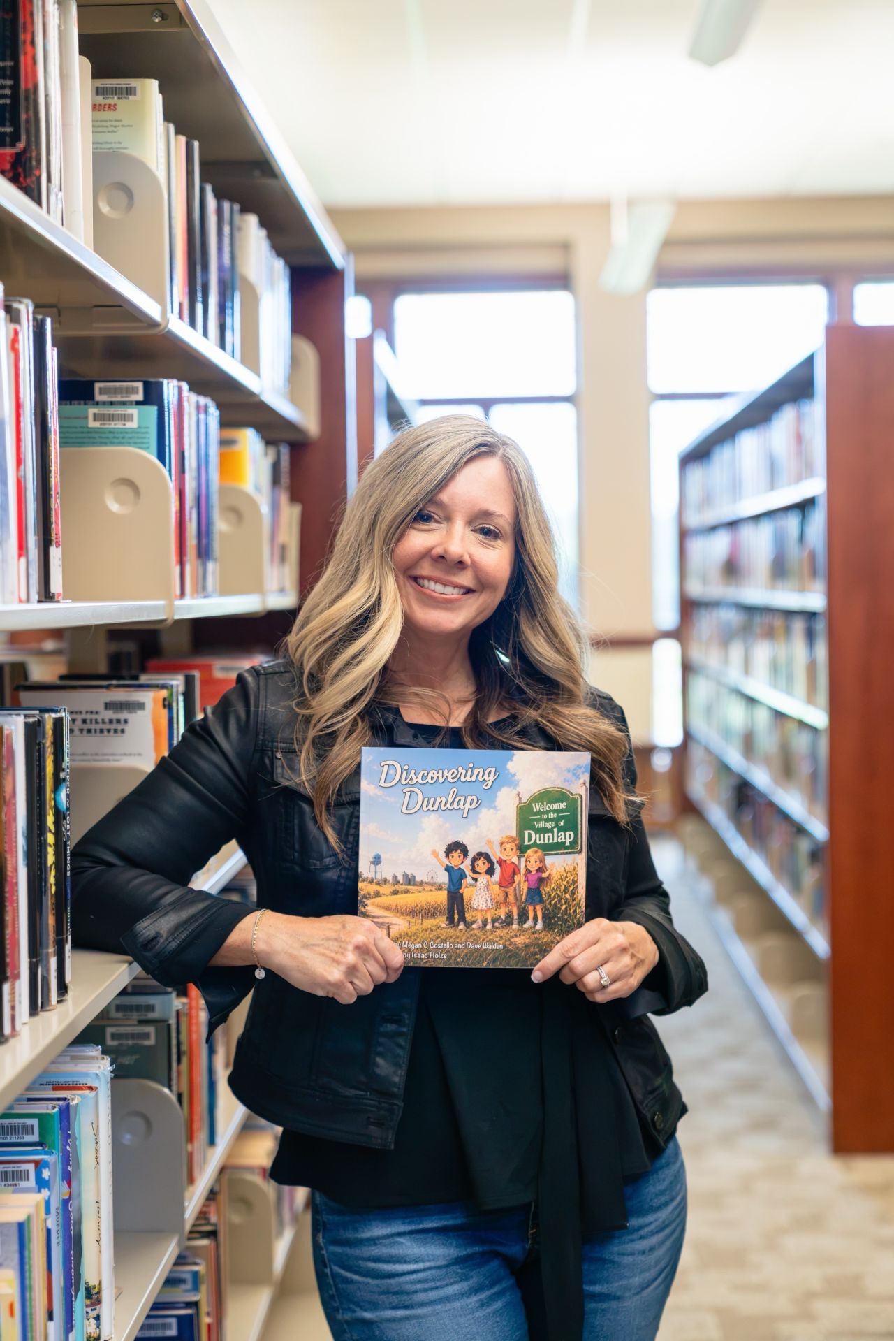 Author Megan Costello holding Discovering Dunlap in a library